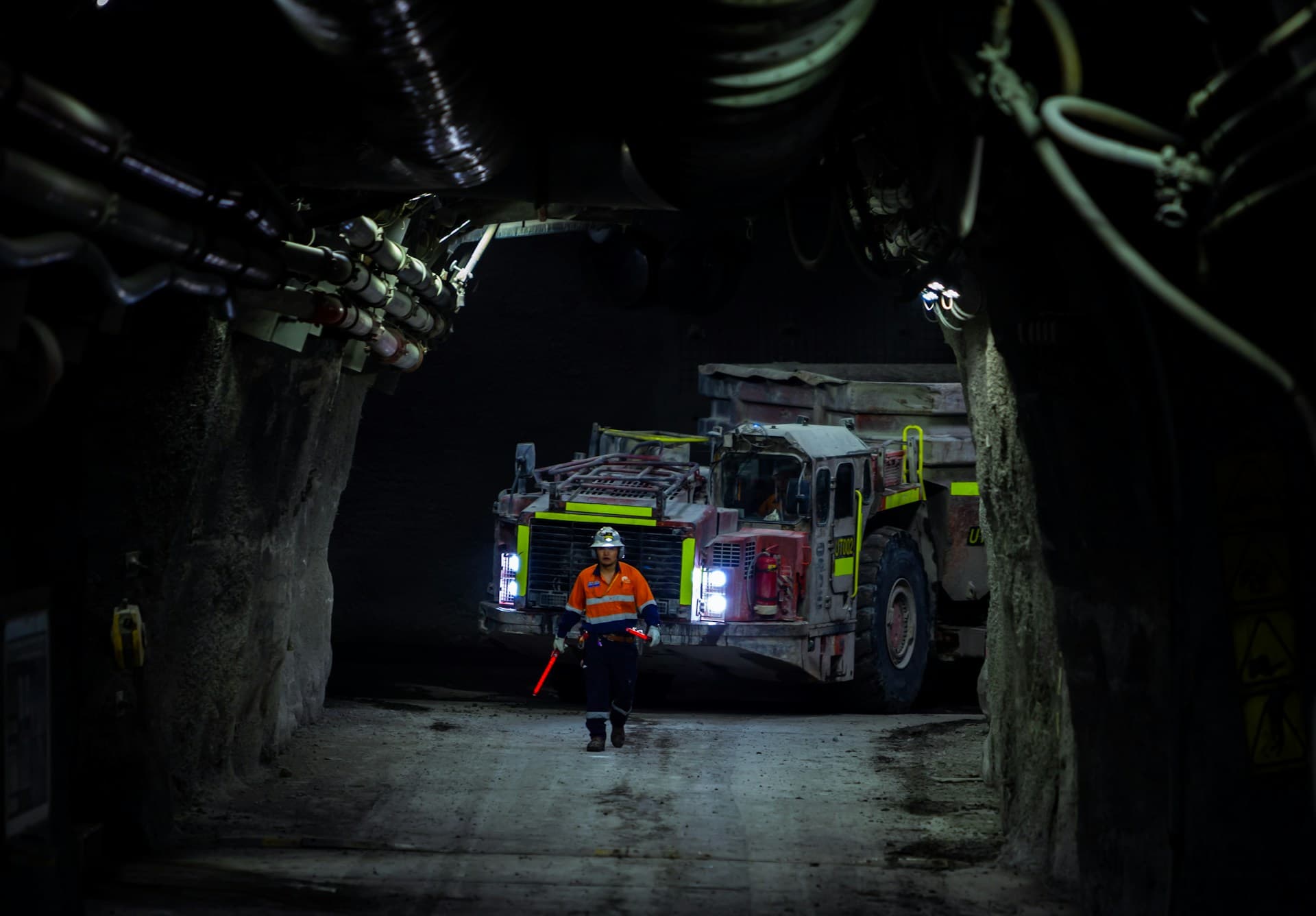 Dark mine tunnel with a single worker silhouetted against distant light